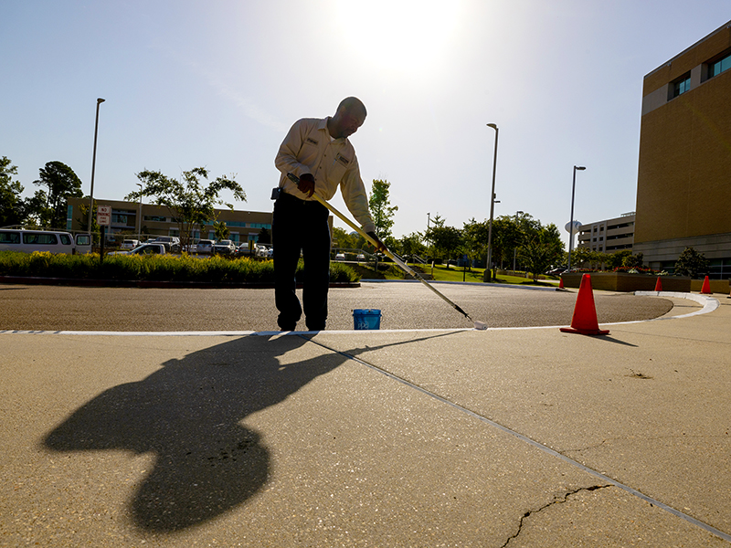UMMC employee Palmer Christian paints early Tuesday morning to avoid dangerous heat later in the day.